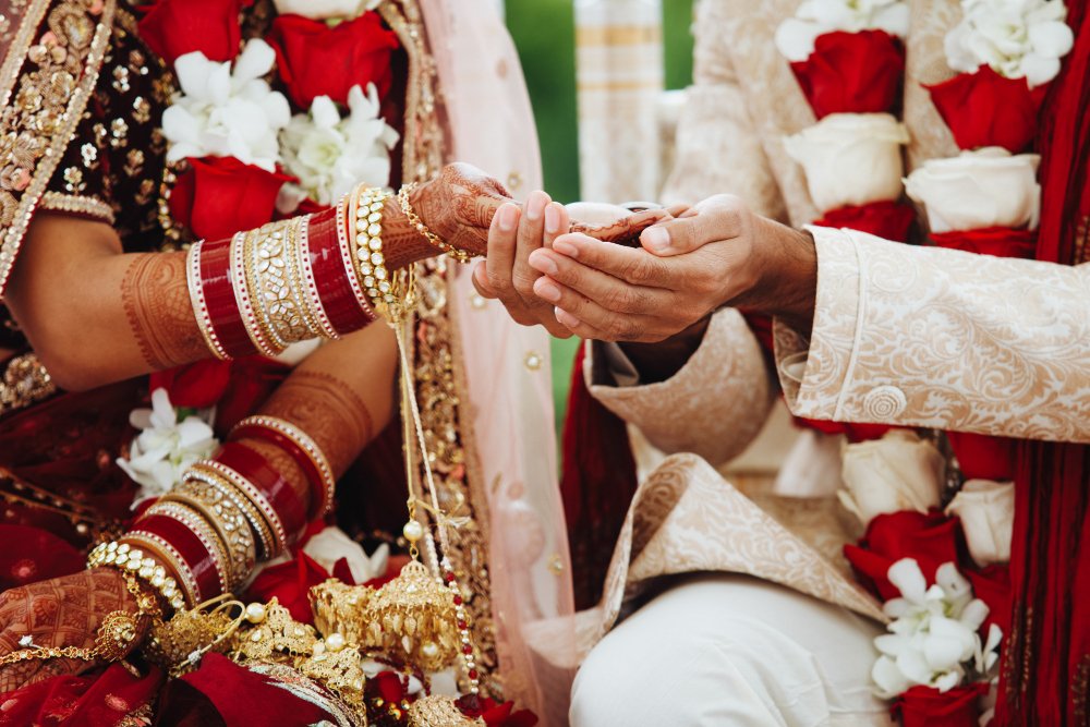 An Indian bride and groom holding hands during a wedding ritual